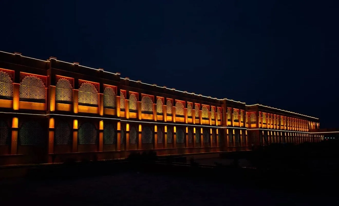 Himmatnagar railway station facade with arched jali screens lit in warm amber at night